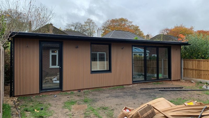 Completed timber clad garden room with black framed doors and windows