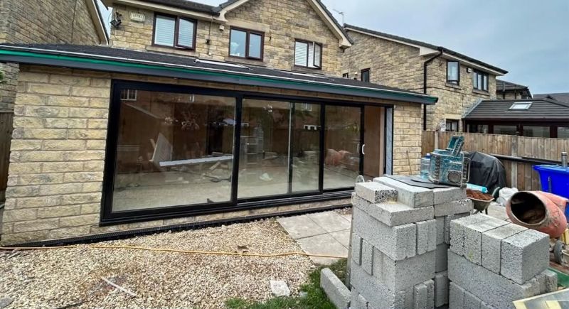 Stone house extension during construction with large glazed doors